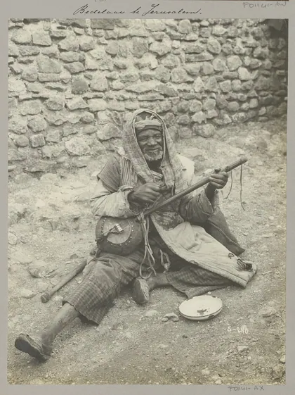 Zittende bedelaar met snaarinstrument in Jeruzalem, 1900