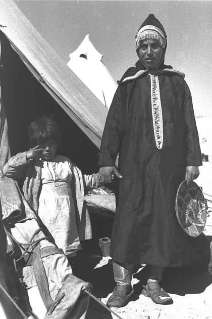 A YEMENITE WOMAN IN TRADITIONAL DRESS WITH HER CHILD AT THE EZRA UBITZARON QUART, 1945